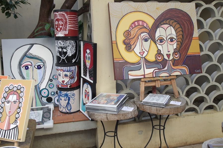 Um monte de pinturas em uma parede, incluindo uma de duas mulheres