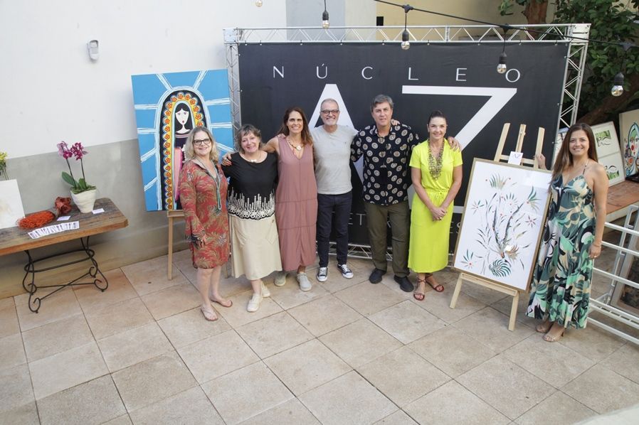 Um grupo de pessoas está posando para uma foto em frente a uma placa que diz nucleo.