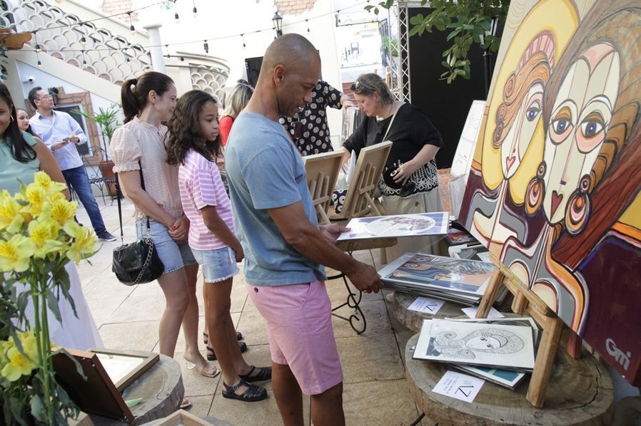 Um grupo de pessoas está olhando para uma pintura em um cavalete.