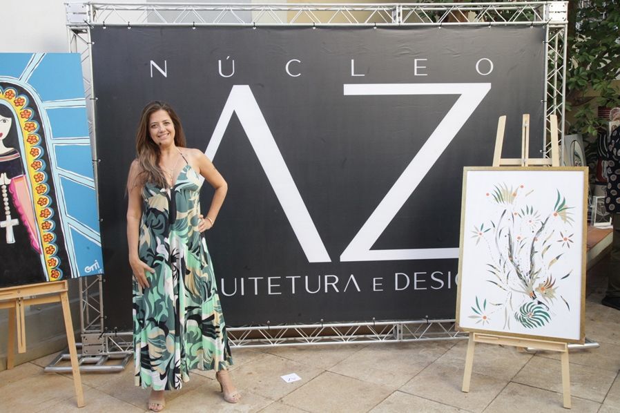Uma mulher com um vestido verde está parada em frente a uma placa que diz nucleo