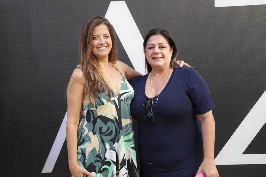 Duas mulheres estão posando para uma foto em frente a uma parede com a letra z escrita nela.