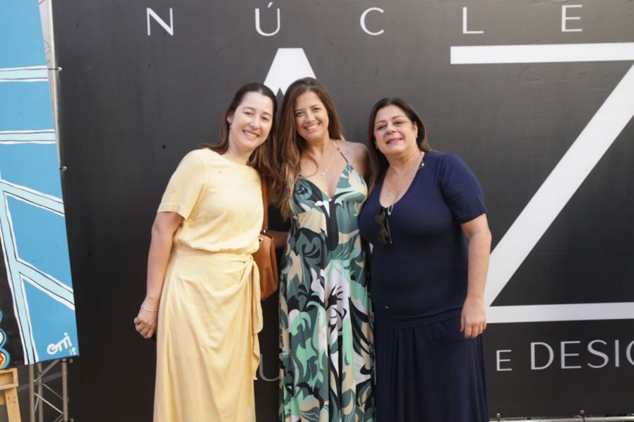 Três mulheres estão posando para uma foto em frente a uma placa que diz nuclear
