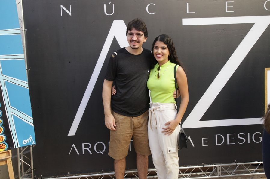 Um homem e uma mulher estão posando para uma foto em frente a uma placa.