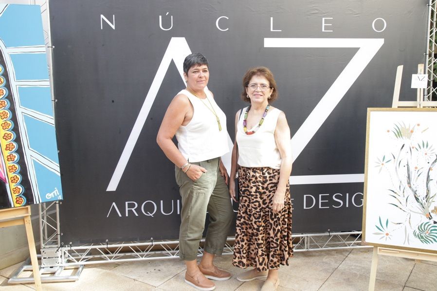 Duas mulheres em pé na frente de uma placa que diz nucleo