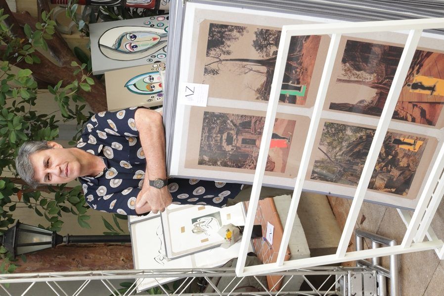Uma mulher está parada em frente a uma exposição de pinturas com o número 7 nela