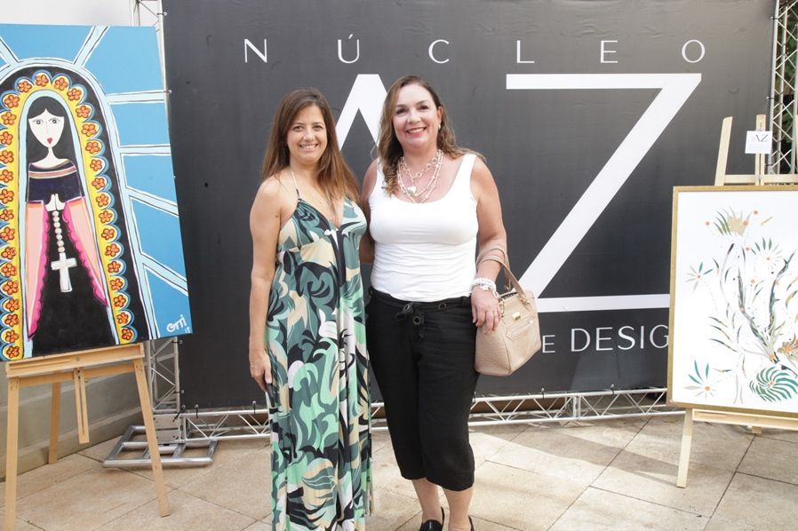 Duas mulheres posam para uma foto em frente a uma placa que diz nucleo