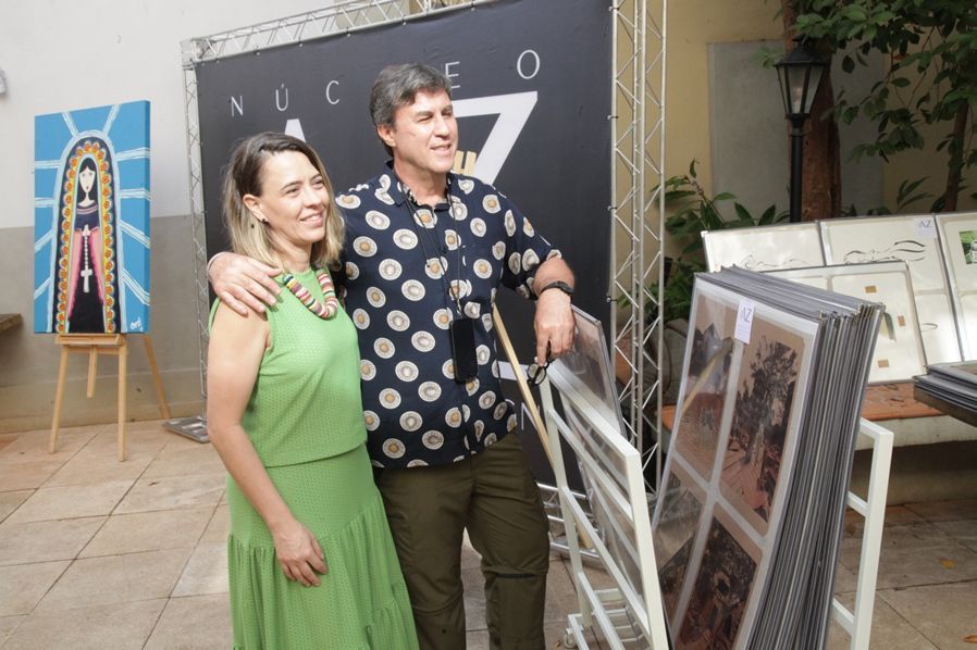 Um homem e uma mulher estão posando para uma foto em frente a uma placa que diz nucleo