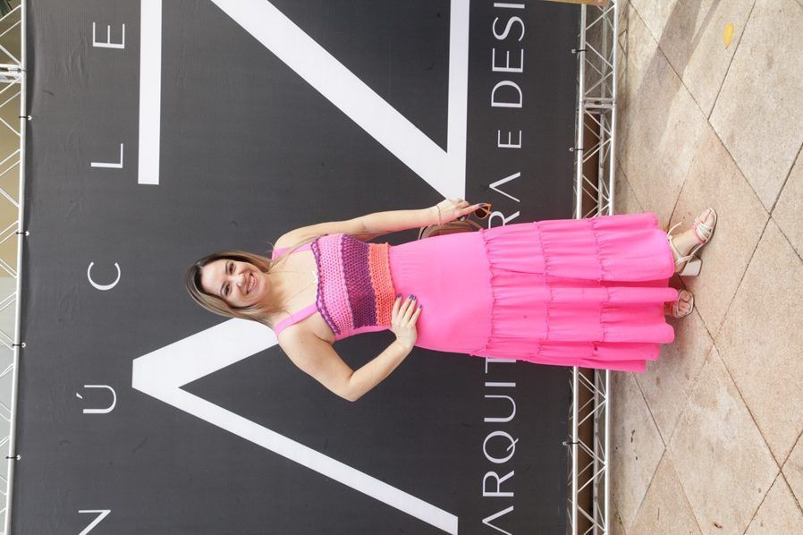 Uma mulher com um vestido rosa está parada em frente a uma placa que diz nuclear