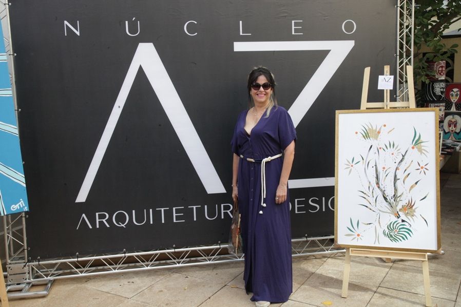 Uma mulher de vestido azul está em frente a uma placa que diz nucleo