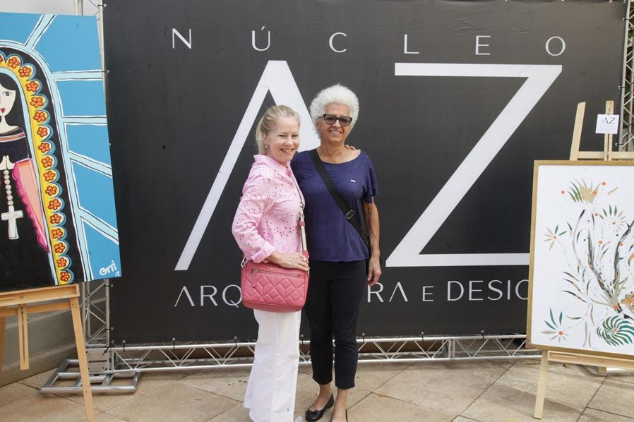 Duas mulheres em pé na frente de uma placa que diz nucleo