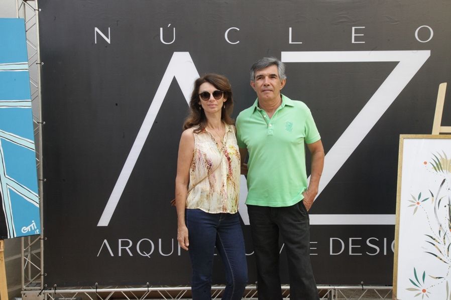 Um homem e uma mulher posam em frente a uma placa que diz nucleo