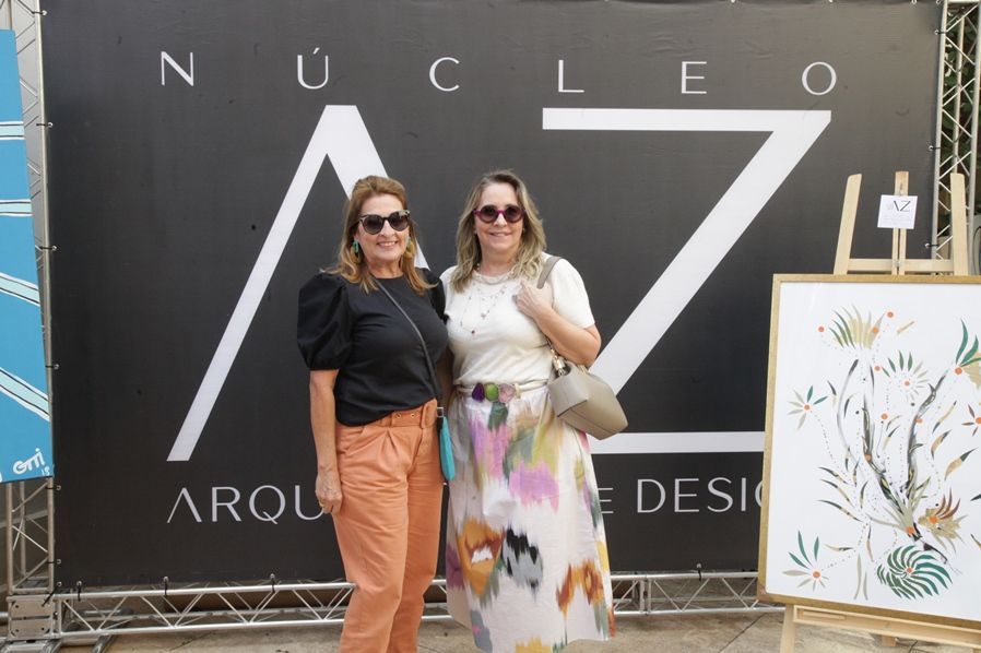 Duas mulheres posam para uma foto em frente a uma placa que diz nucleo