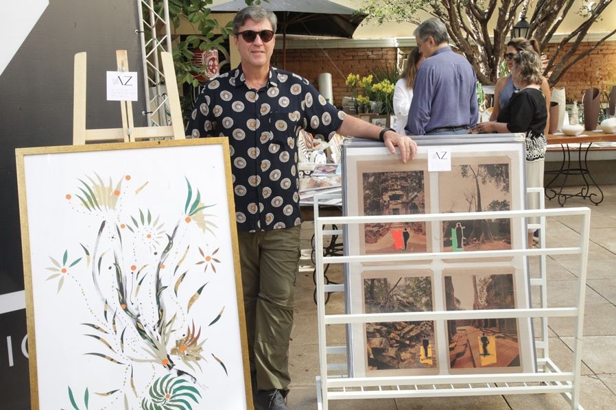 Um homem com uma camisa de bolinhas está segurando uma pintura emoldurada