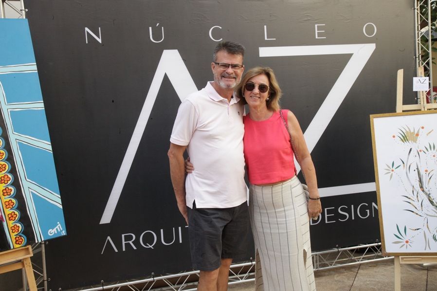 Um homem e uma mulher estão posando para uma foto em frente a uma placa que diz nucleo