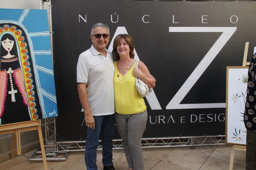Um homem e uma mulher em pé na frente de uma placa que diz nucleo
