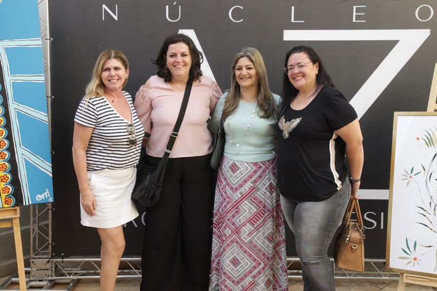 Um grupo de mulheres está posando para uma foto em frente a uma placa que diz nucleo