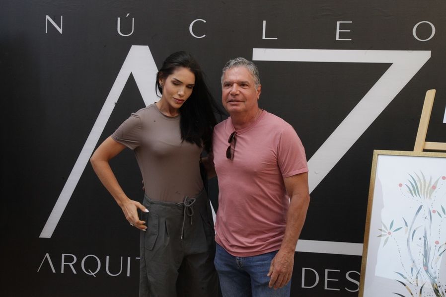 Um homem e uma mulher posam em frente a uma placa que diz nucleo