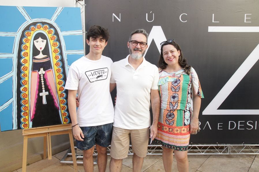 Um homem, um menino e uma mulher estão posando para uma foto em frente a uma placa que diz nuclear