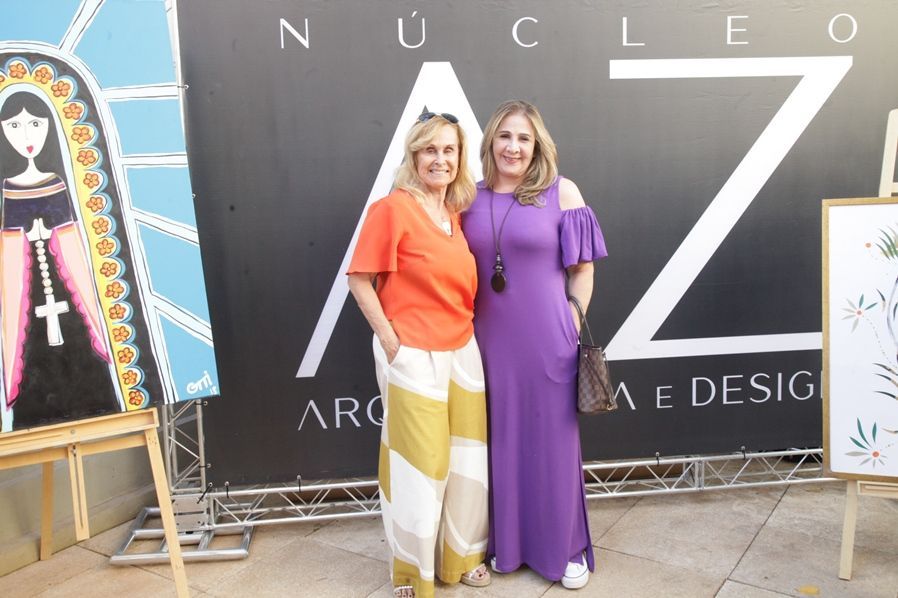 Duas mulheres em pé na frente de uma placa que diz nucleo
