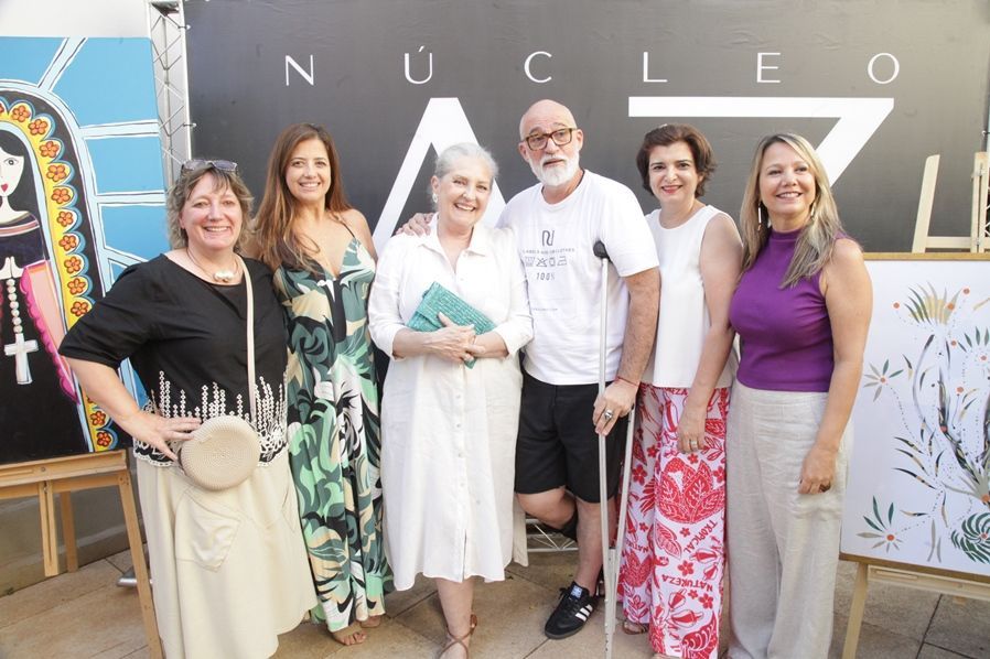 Um grupo de pessoas está posando para uma foto em frente a uma placa que diz nucleo.
