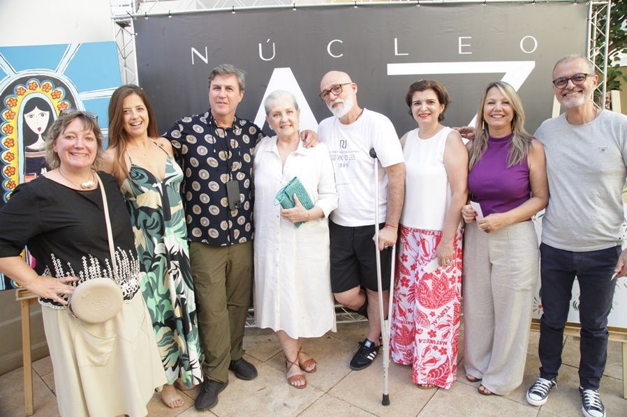 Um grupo de pessoas em pé em frente a uma placa que diz nucleo