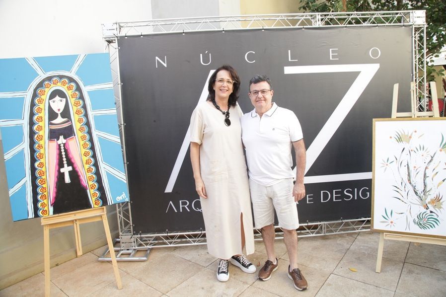 Um homem e uma mulher estão posando para uma foto em frente a uma placa que diz nucleo