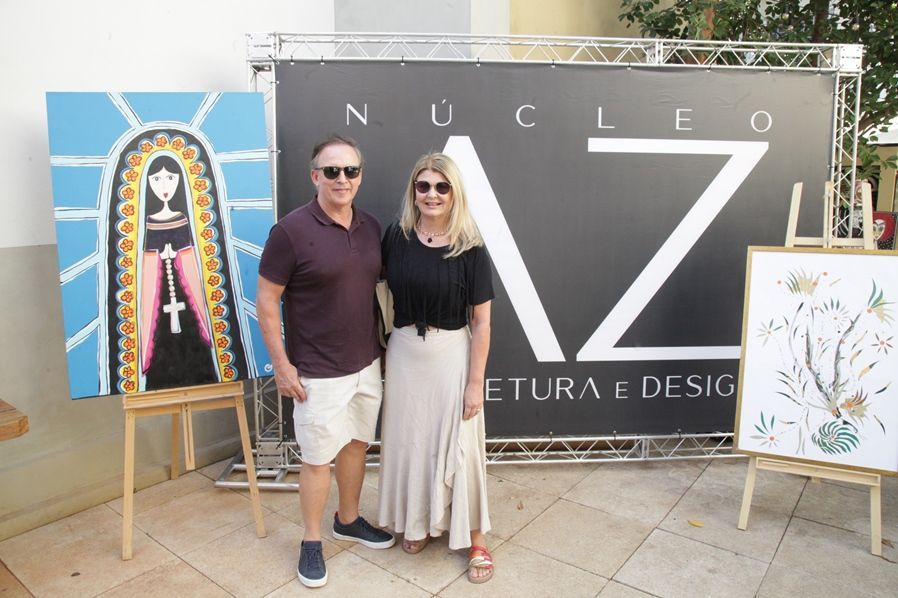 Um homem e uma mulher estão parados em frente a uma placa que diz nucleo az