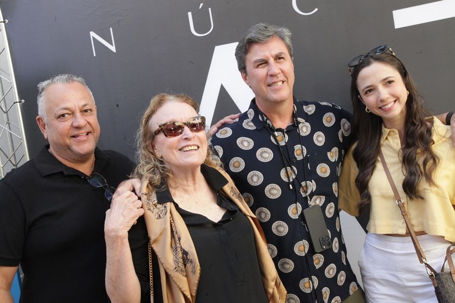 Um grupo de pessoas está posando para uma foto em frente a uma placa.