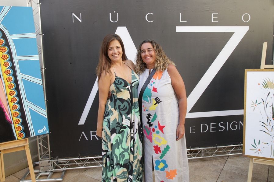 Duas mulheres posam para uma foto em frente a uma placa que diz nucleo