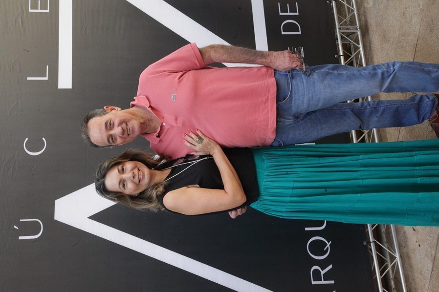 Um homem e uma mulher estão parados um ao lado do outro em frente a uma placa.