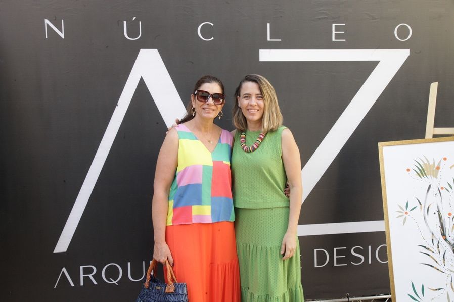 Duas mulheres posando para uma foto em frente a uma placa que diz nucleo