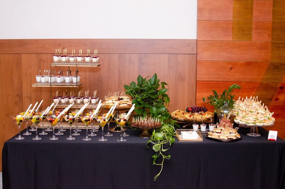 Uma mesa de bufê com muita comida e taças de vinho.