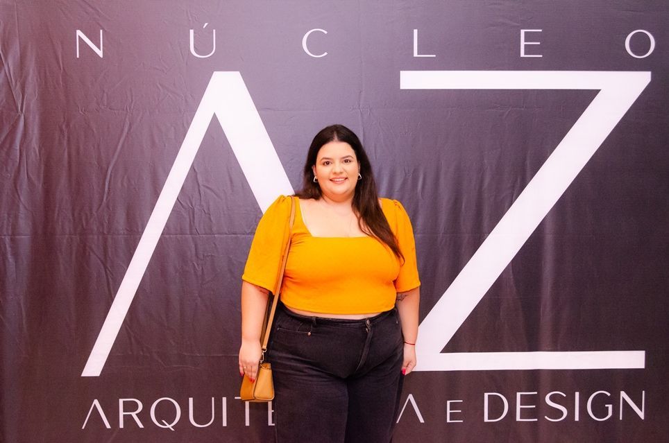 Uma mulher está parada em frente a uma placa que diz nucleo ae design