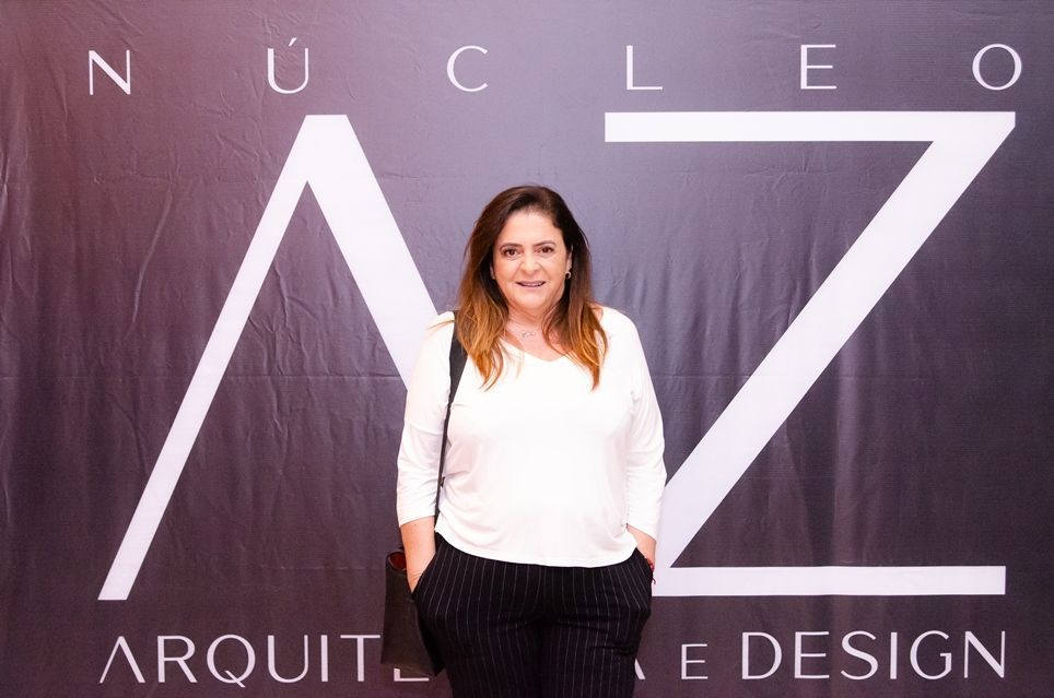 Uma mulher está parada em frente a uma placa que diz nucleo arquitetura design