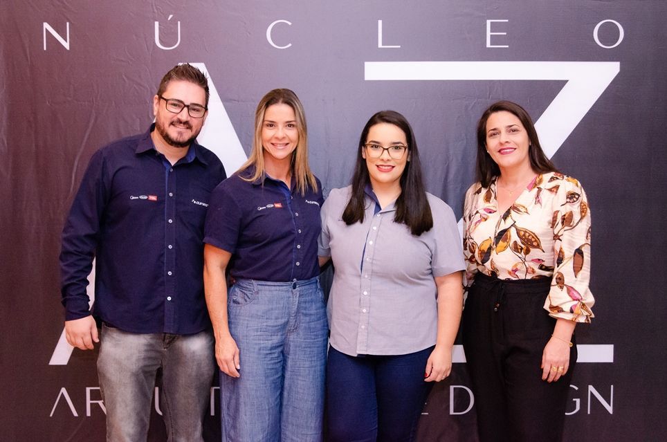 Um grupo de pessoas está posando para uma foto em frente a uma placa que diz nucleo