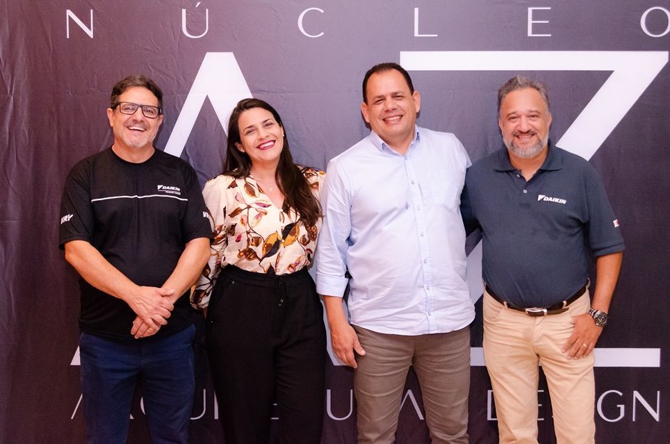 Um grupo de pessoas está posando para uma foto em frente a uma placa que diz nucleo.