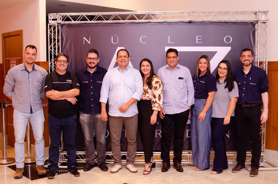 Um grupo de pessoas está posando para uma foto em frente a um banner.