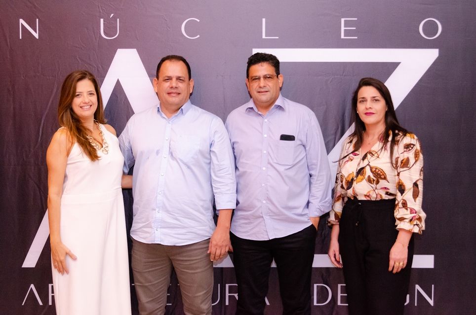 Um grupo de pessoas em pé em frente a uma placa que diz nucleo
