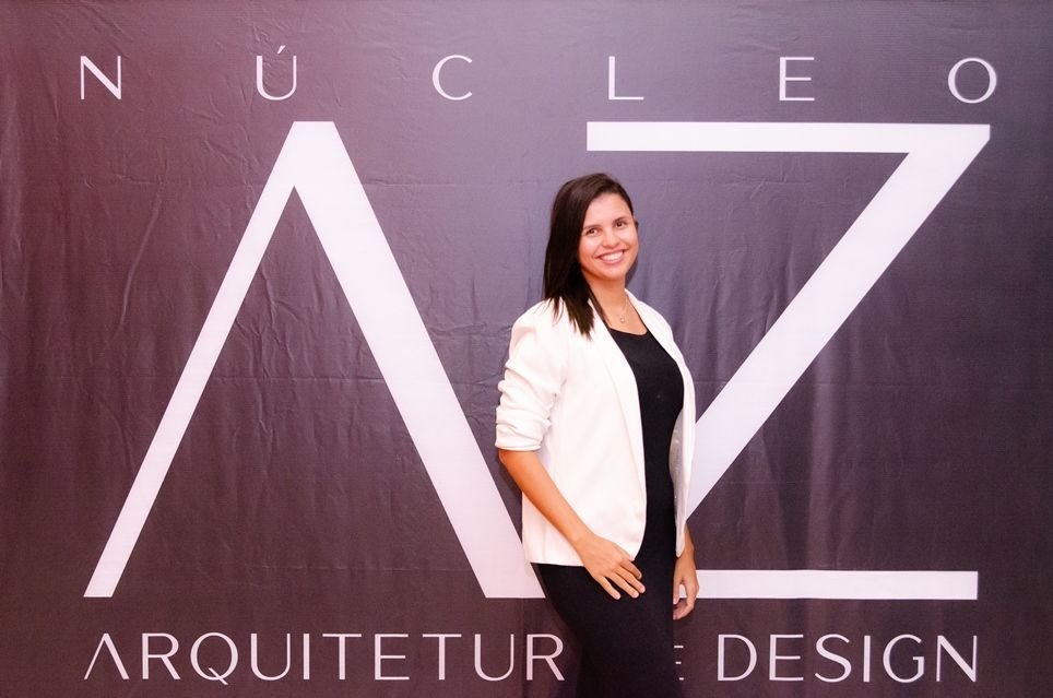 Uma mulher está em frente a uma placa que diz nucleo arquiteto design