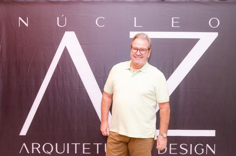 Um homem está parado em frente a uma placa que diz nucleo arquiteti design