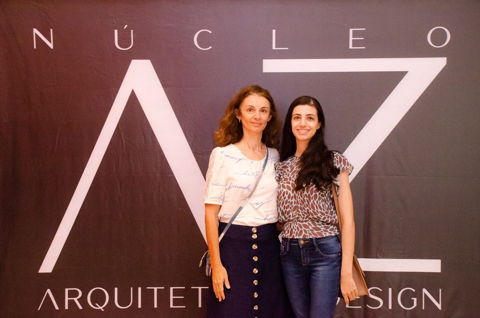 Duas mulheres posam para uma foto em frente a uma placa que diz nucleo
