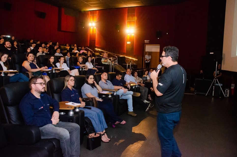Um homem está fazendo uma apresentação para um grupo de pessoas em um teatro.