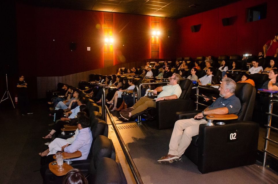 Um grupo de pessoas está sentado em um cinema assistindo a um filme.