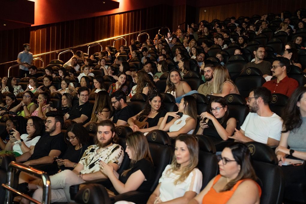 Um grande grupo de pessoas está sentado em um cinema assistindo a um filme.