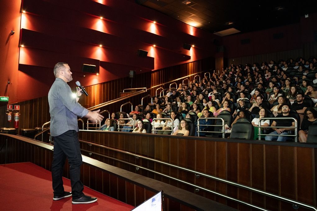 Um homem está fazendo uma apresentação para uma grande multidão em um teatro.
