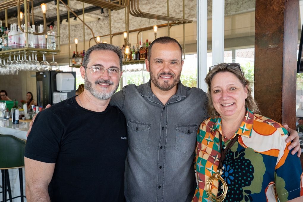 Três pessoas estão posando para uma foto em um restaurante.
