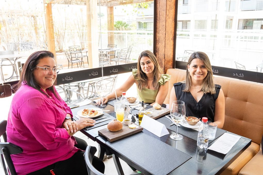 Três mulheres estão sentadas à mesa em um restaurante.