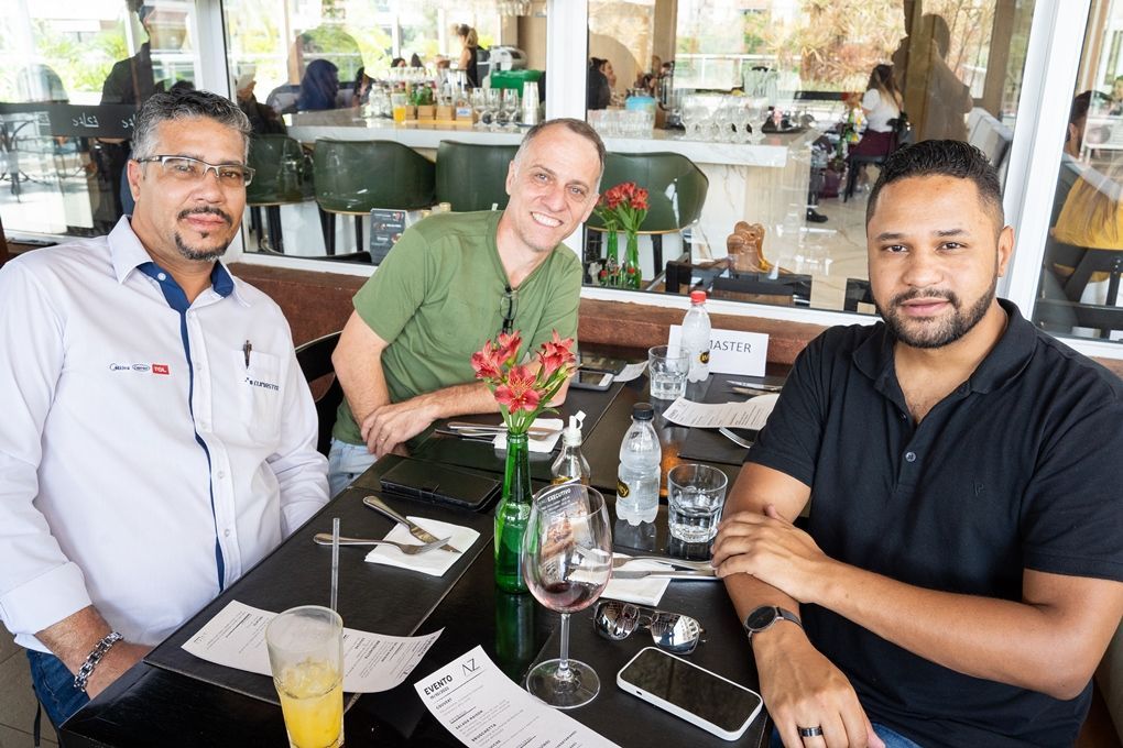 Três homens estão sentados à mesa em um restaurante.