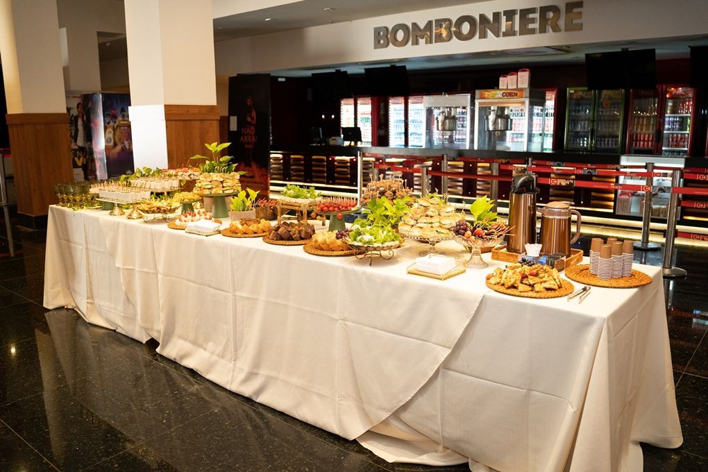 Uma longa mesa com comida em frente a uma placa que diz bomboniere