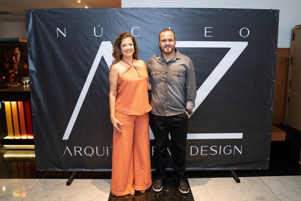 Um homem e uma mulher posam para uma foto em frente a uma placa que diz arquitetura design